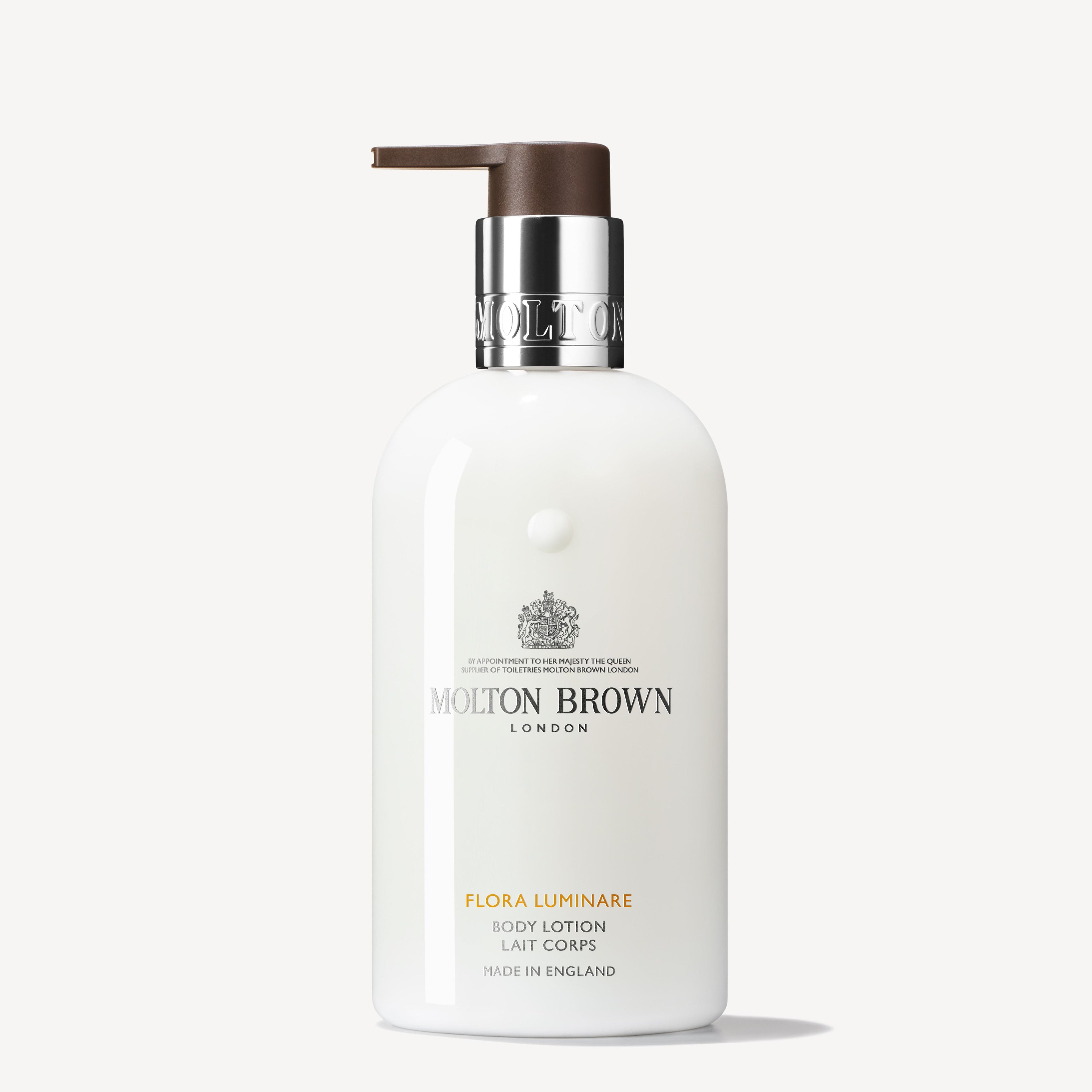 The Flora Luminare Body Lotion 300ml from MoltonBrown Cyprus features a white bottle with a pump dispenser, elegantly displaying the brand's label and logo adorned with silver and brown accents. This fragranced moisturizer, crafted in England, adds a luxurious touch to your skincare routine.