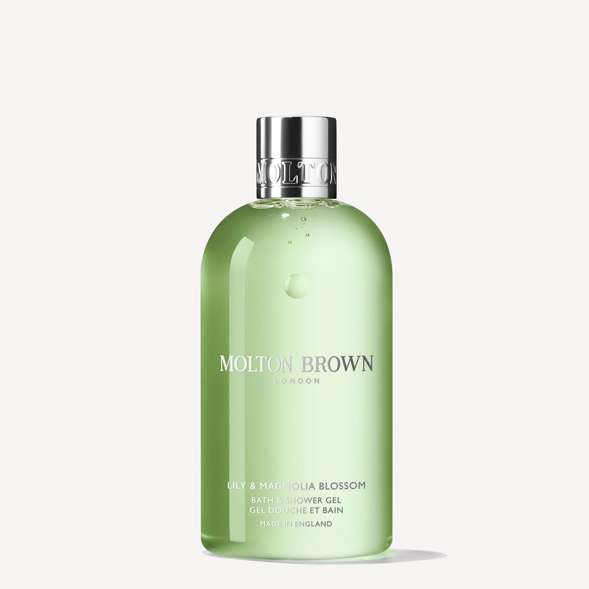 A 300ml bottle of MoltonBrown Cyprus Lily & Magnolia Blossom Bath & Shower Gel, featuring a silver cap and green packaging. The brand logo and product details are displayed in white text on the front. Enriched with lily of the valley notes, it offers a captivating floral experience.