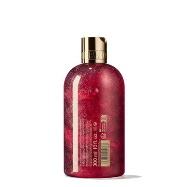 Introducing the MoltonBrown Cyprus Merry Berries & Mimosa Bath & Shower Gel: a 300ml bottle featuring a captivating deep pink floral-fruity body wash with a shimmering finish and a gold cap. Adorned with text in gold, the label highlights its enticing blend of candied red berries, offering an exquisite and luxurious aesthetic perfect for your seasonal bathing ritual.