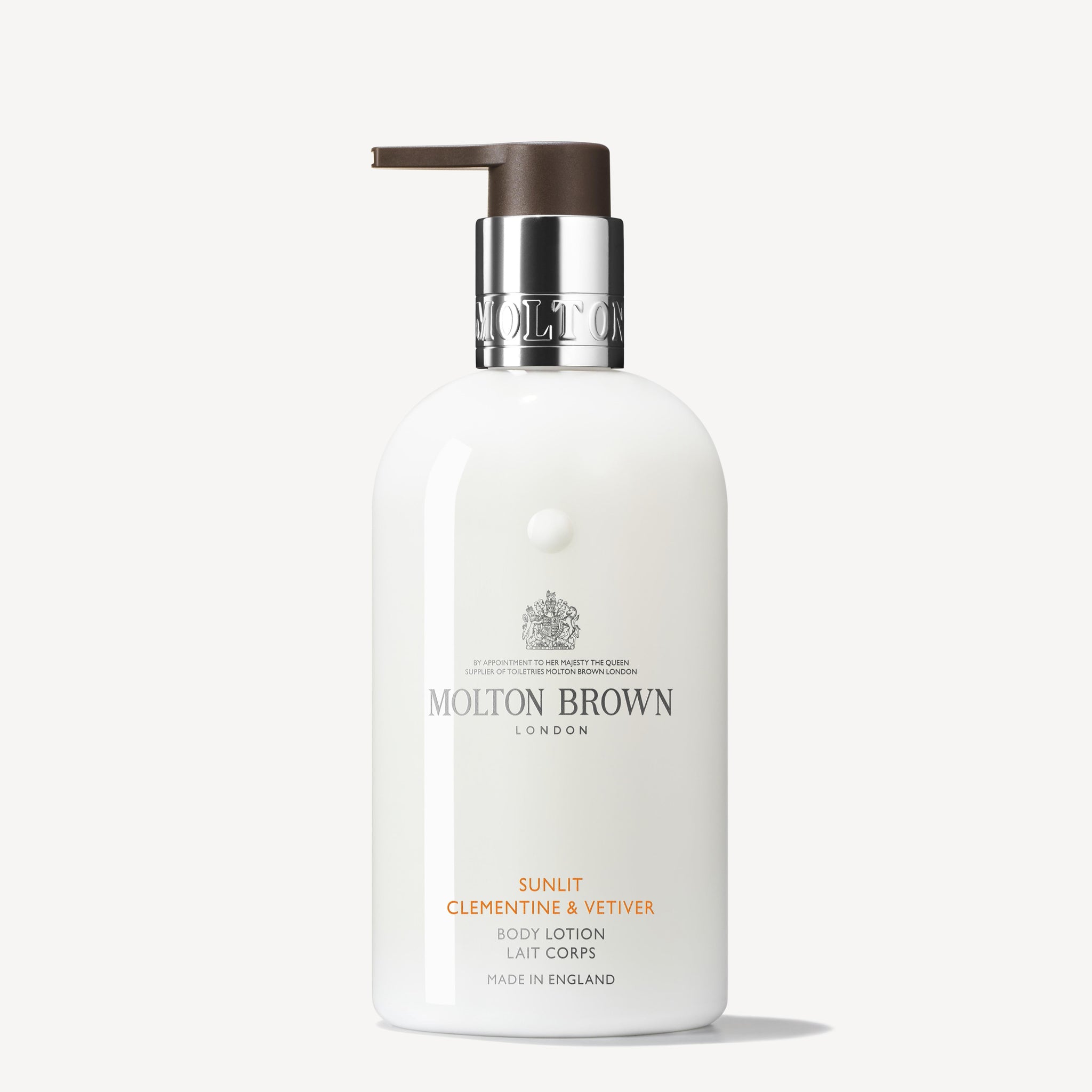 A white bottle of Sunlit Clementine & Vetiver Body Lotion by MoltonBrown Cyprus, featuring a dark brown pump. The label highlights its infusion with clementine zest. Proudly Made in England.