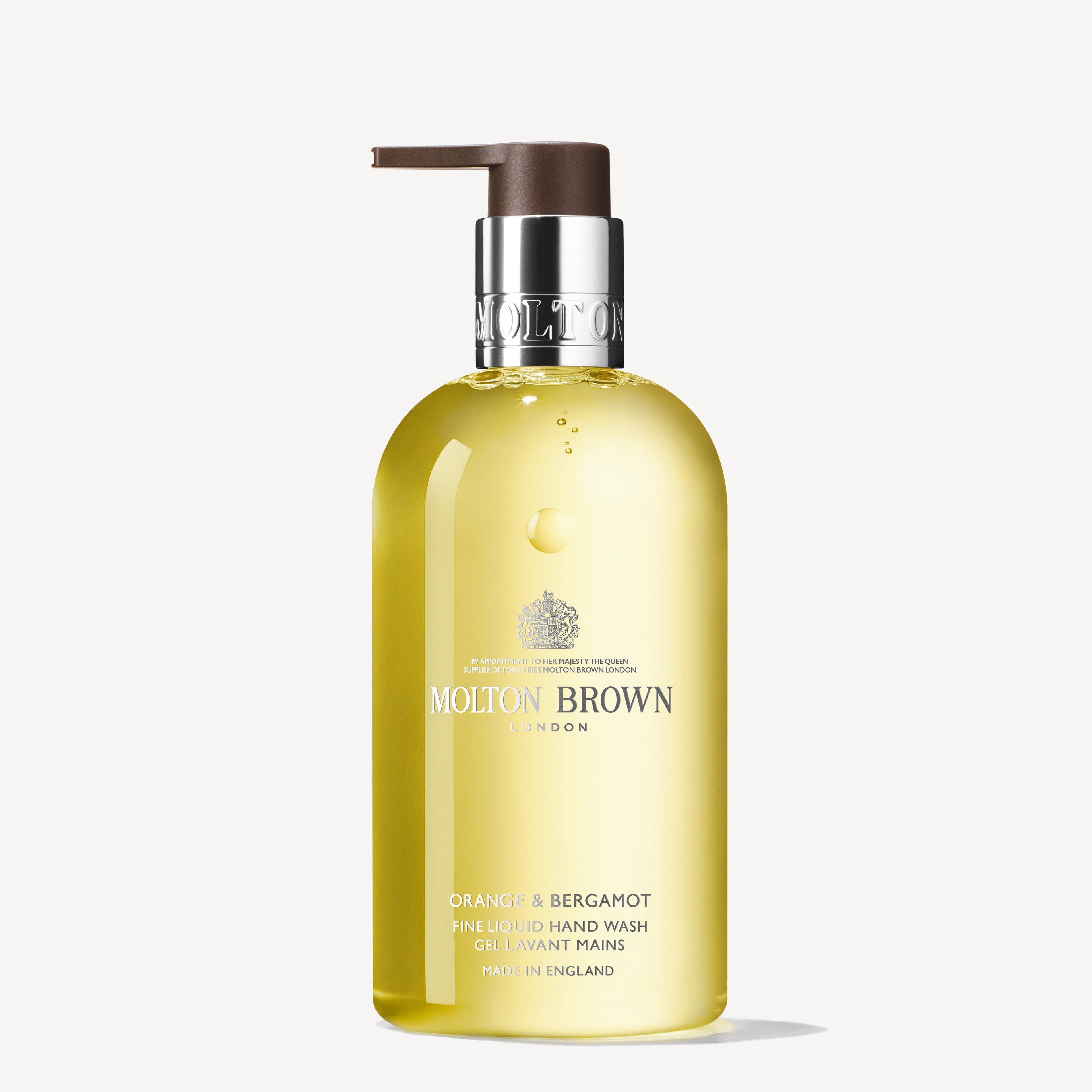 The Orange & Bergamot Fine Liquid Hand Wash 300ml by MoltonBrown Cyprus comes in a clear pump bottle showcasing a pale yellow liquid infused with neroli. The label features silver text, while the brown pump contributes to its elegance. This exquisite product is proudly made in England.