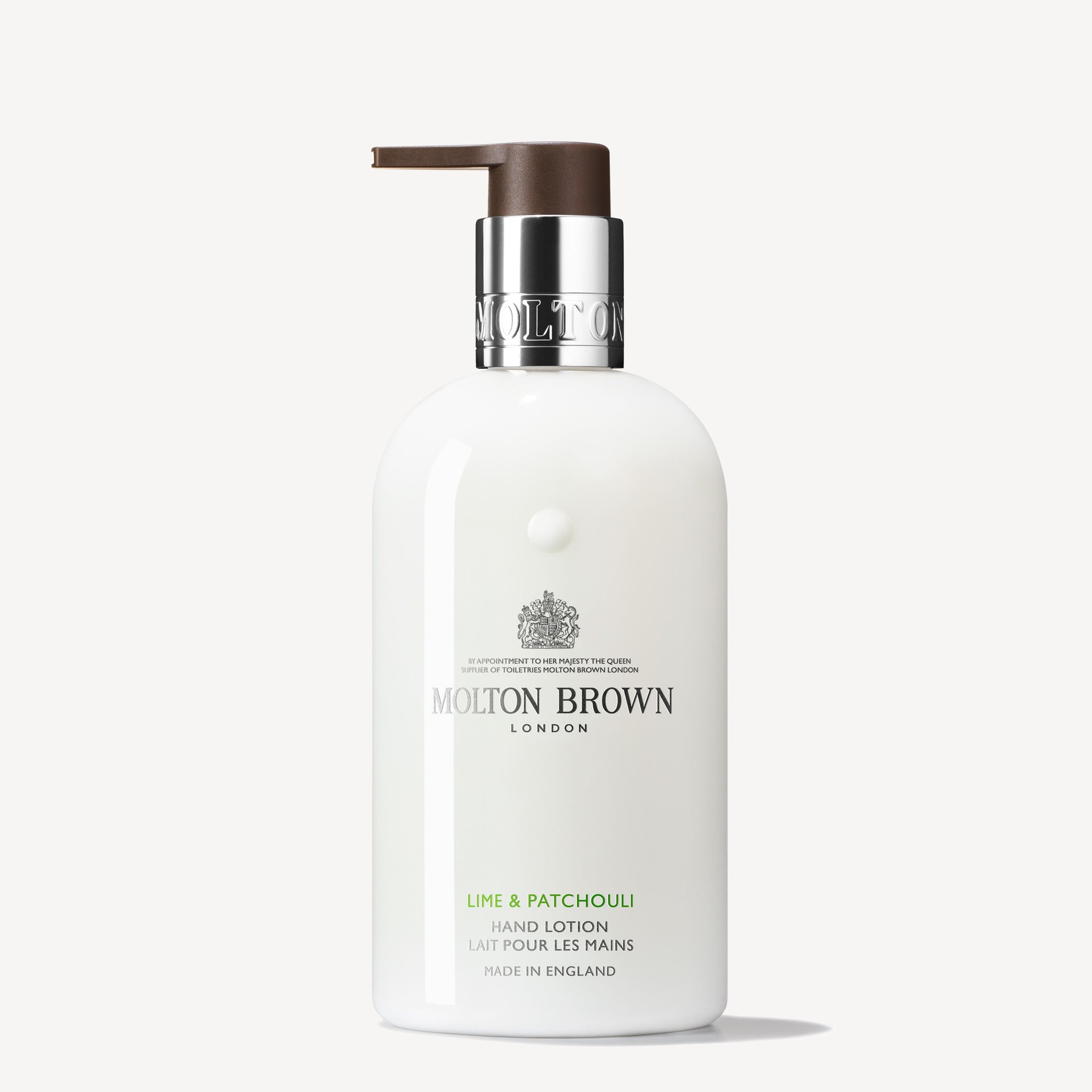 A 300ml bottle of MoltonBrown Cyprus Lime & Patchouli Hand Lotion, complete with a pump dispenser. The packaging is white with a silver and brown cap and showcases elegant branding. Infused with makrut lime leaves, this lotion exudes luxury and bears the "Made in England" mark at the bottom.