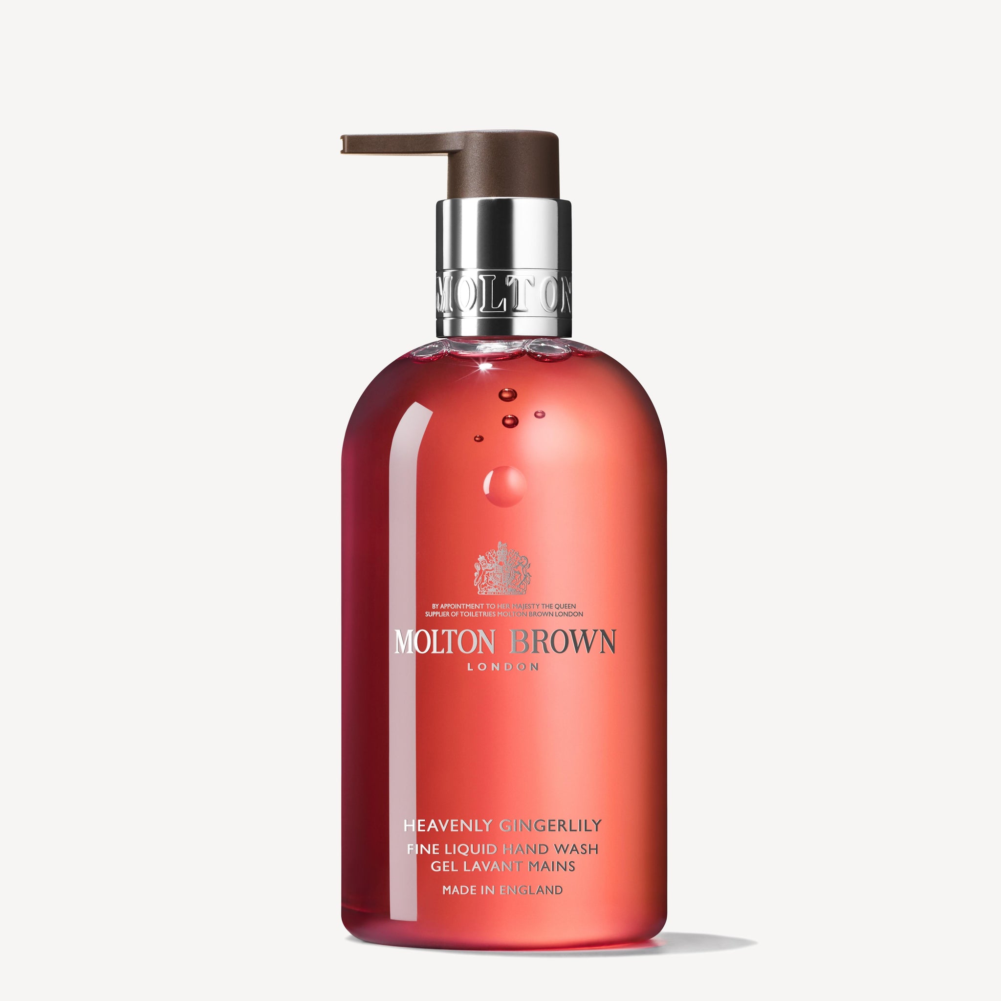 A bottle of MoltonBrown Cyprus Heavenly Gingerlily Fine Liquid Hand Wash 300ml. The translucent container highlights the orange-pink, floral-rich liquid within and is equipped with a brown pump dispenser. The label features white text that provides brand and product details, capturing the spirit of Tahitian shores.