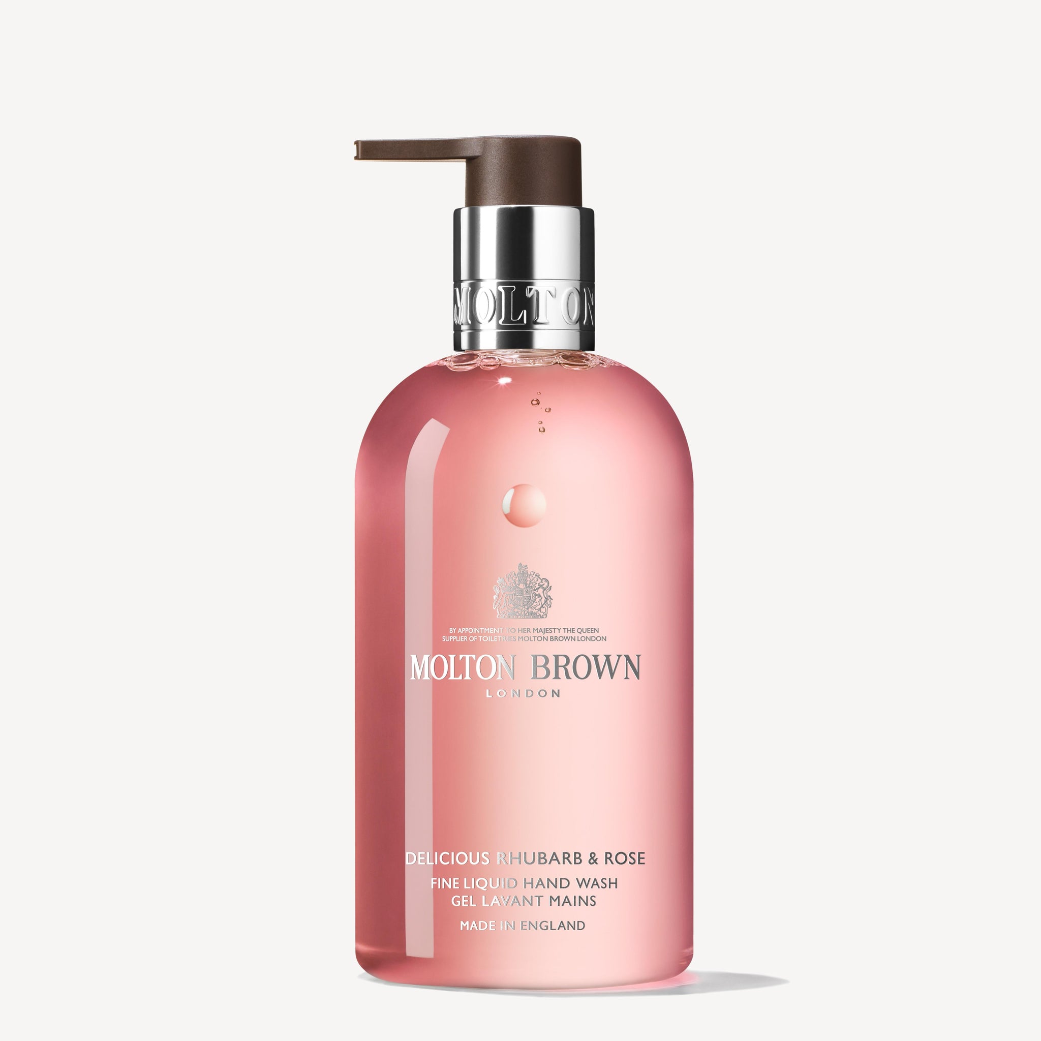 A pink bottle of Delicious Rhubarb & Rose Fine Liquid Hand Wash by MoltonBrown Cyprus, featuring a pump dispenser and the uplifting fragrance of Yorkshire Rhubarb & Rose. Made in England, the branding and details are elegantly displayed in white text.