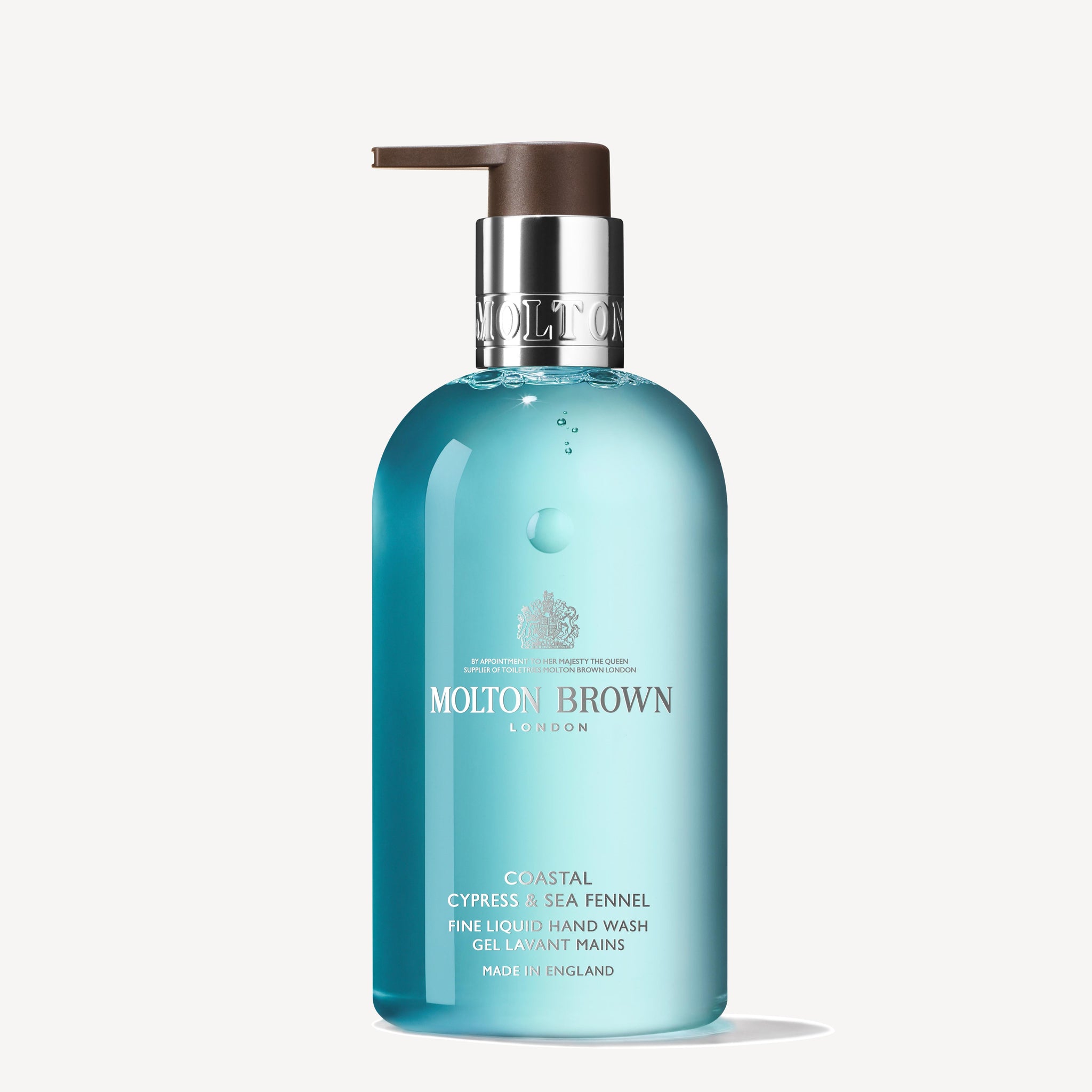 A 300ml bottle of MoltonBrown Cyprus Coastal Cypress & Sea Fennel Fine Liquid Hand Wash with a pump dispenser. The translucent turquoise packaging highlights marine notes and proudly states that it is made in England.