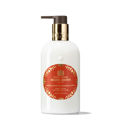 A white bottle of MoltonBrown Cyprus Marvellous Mandarin & Spice Hand Lotion with a pump dispenser. The red label, adorned with decorative golden foliage, features the Marylebones Mandarin & Spice scent with a hint of cinnamon. The gold cap proudly bears the brand's embossed name.