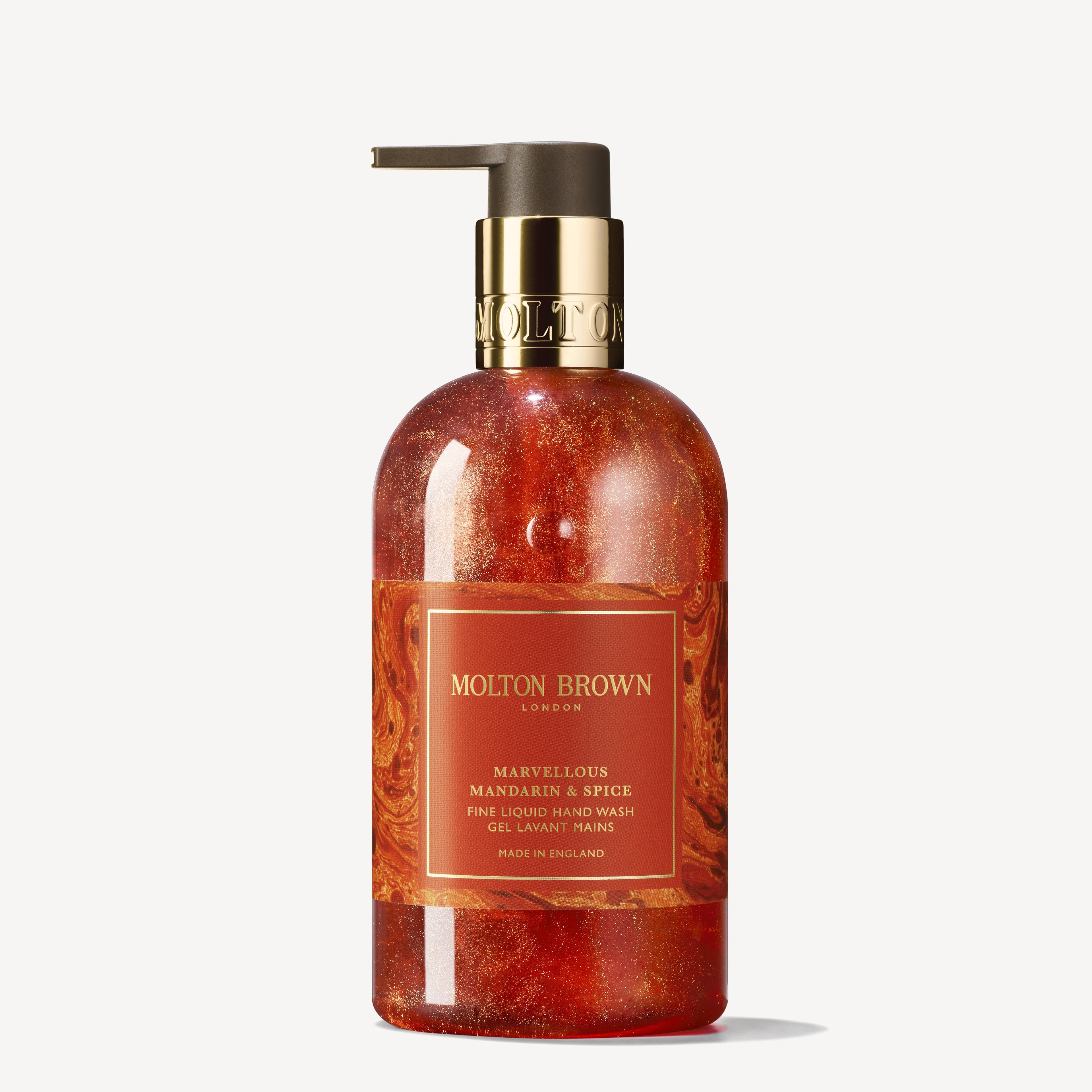 A 300ml bottle of Marvellous Mandarin & Spice Fine Liquid Hand Wash from MoltonBrown Cyprus, featuring a pump dispenser. Its marbled red and orange design evokes a Christmas cake, and the brown label with gold text hints at the juicy mandarin aroma inside.