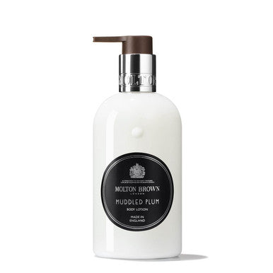 A white bottle of MoltonBrown Cyprus Muddled Plum Body Lotion 300ml, fragranced to perfection, features a silver collar and a brown pump. The label, with its black background and white text alongside a decorative crest, enhances the allure of this luxurious moisturizer.