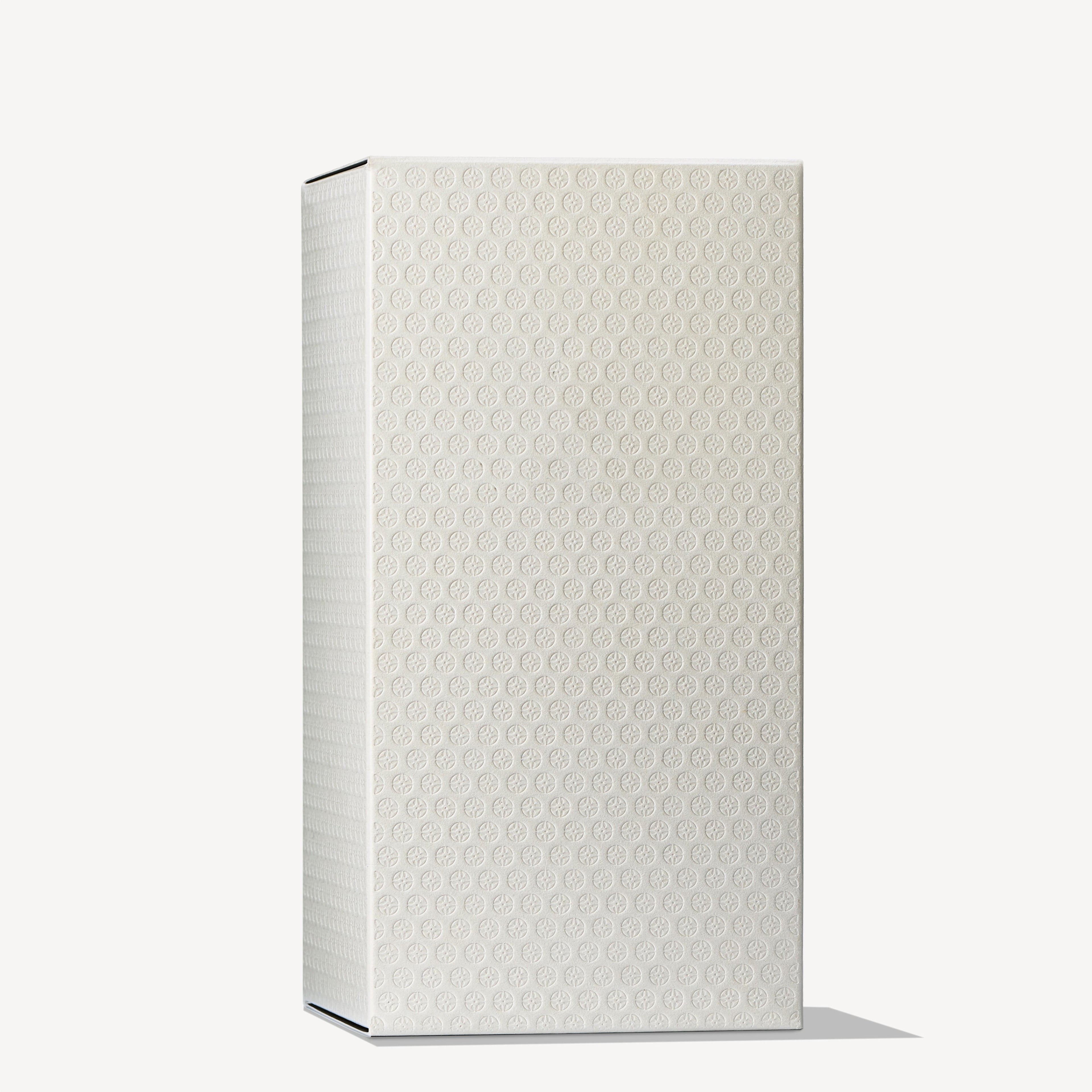 The Orange & Bergamot Eau de Toilette 100ml by MoltonBrown Cyprus stands upright against a plain background in a tall rectangular box with a textured white surface. The pattern on the box is reminiscent of small, embossed circles, capturing the elegant simplicity of an Eau de Toilette bottle, as shadows are cast along its bottom edge.