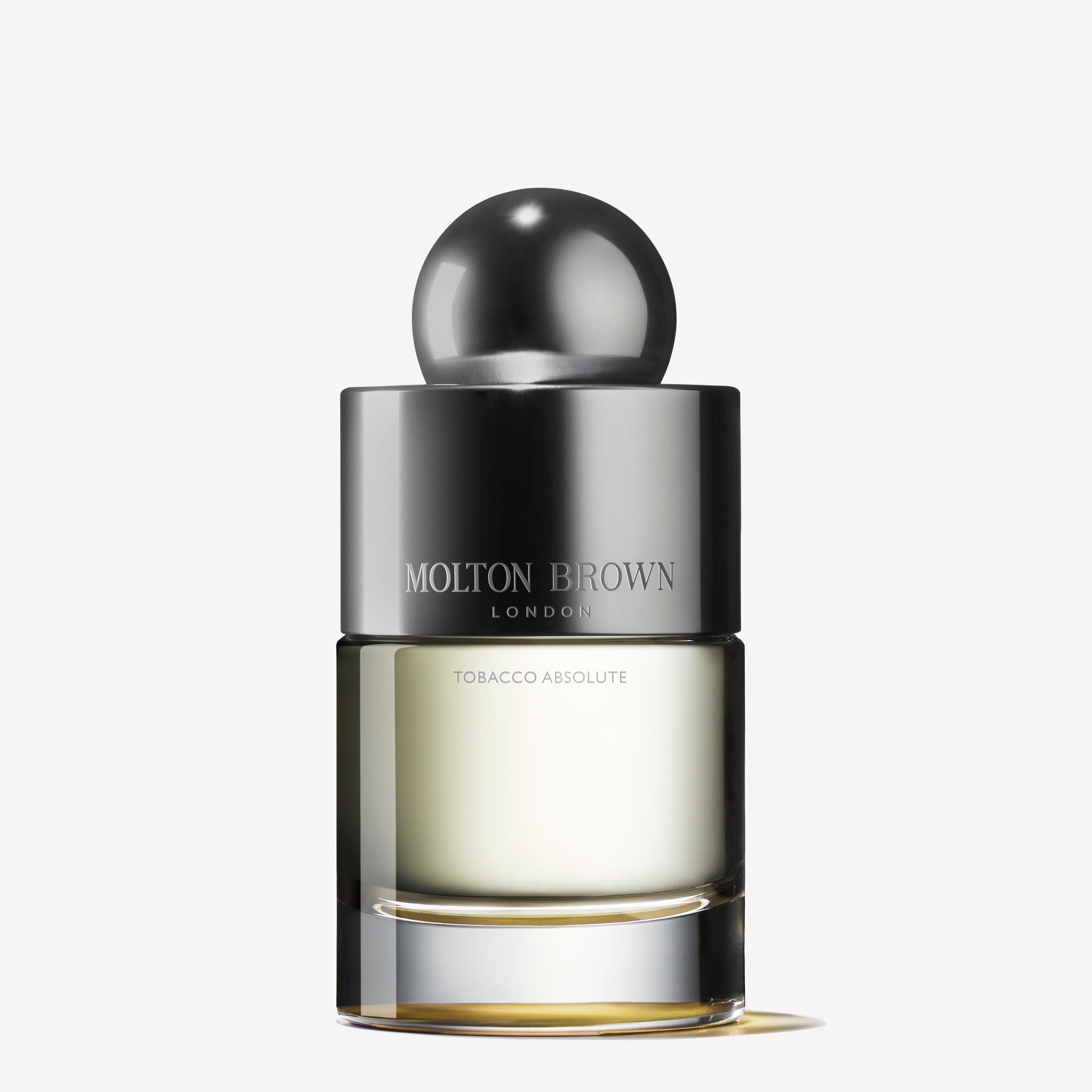 The 100ml bottle of Tobacco Absolute Eau de Toilette by MoltonBrown Cyprus exudes a woody fragrance, showcasing a dark spherical cap and a gradient glass body that highlights the perfume inside.