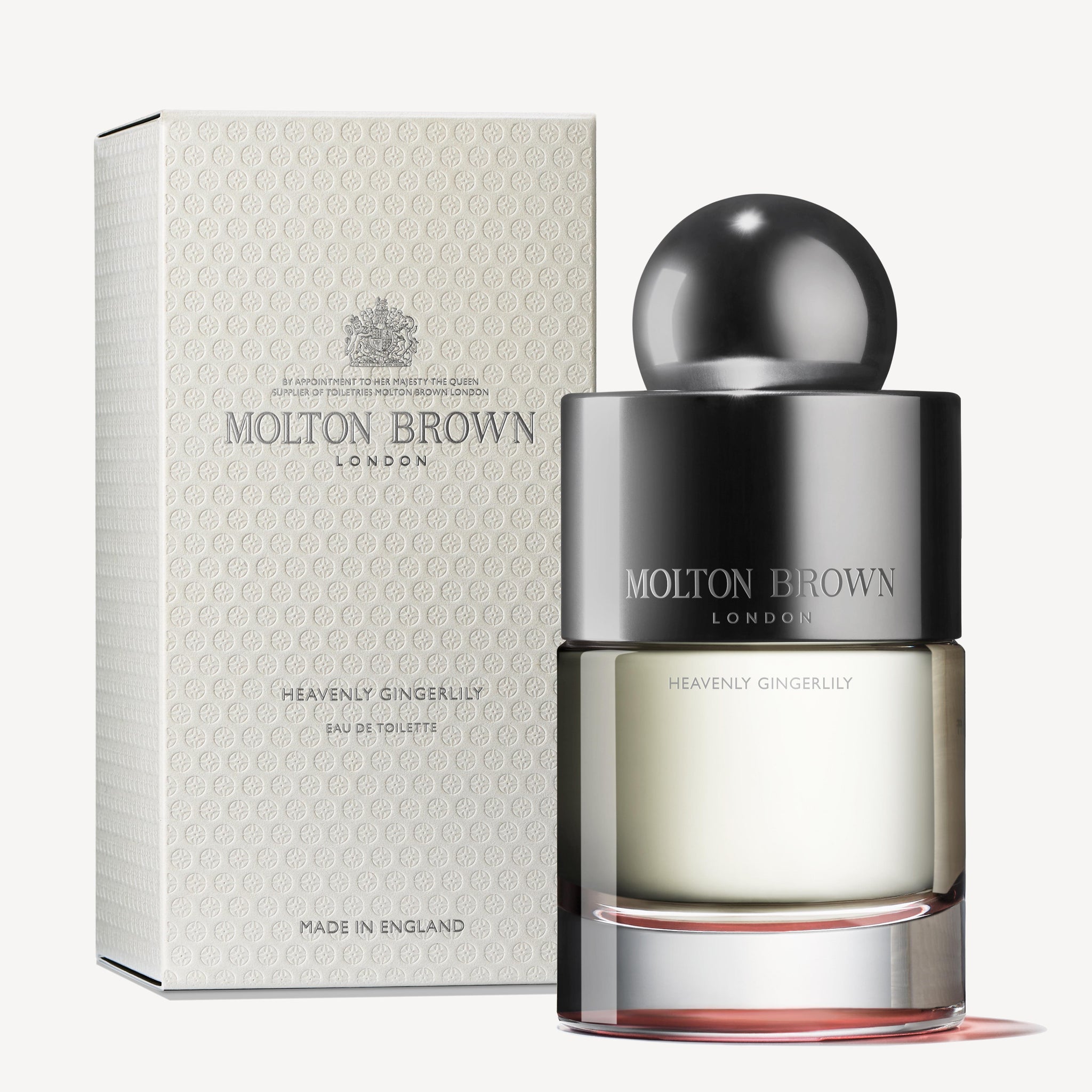 A MoltonBrown Cyprus perfume bottle, named Heavenly Gingerlily Eau de Toilette 100ml, featuring a large round cap, is placed next to its coordinating textured box, both highlighting the same branding and capturing the essence of a Polynesian lagoon.