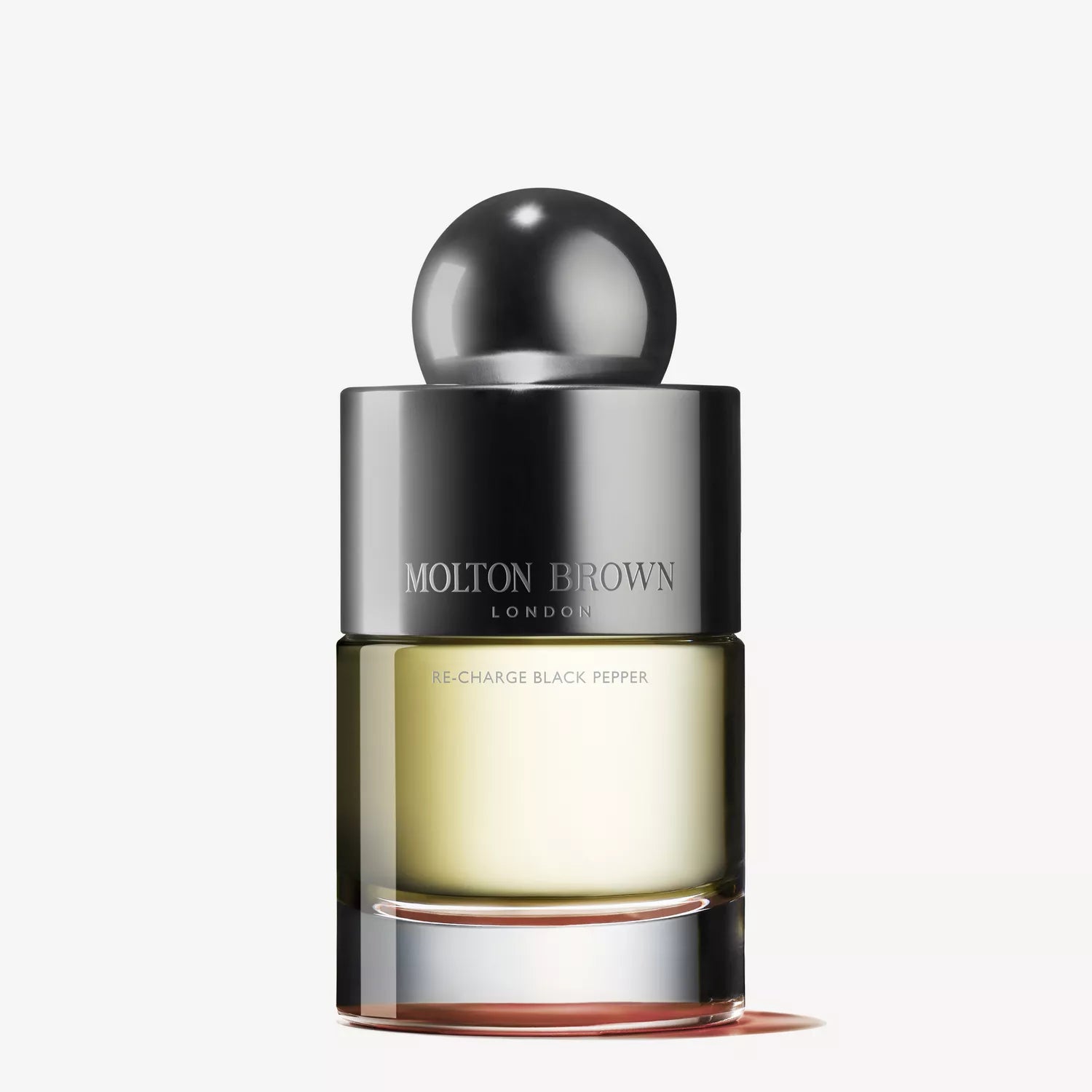 The Molton Brown Cyprus Re-charge Black Pepper Eau de Toilette (100ml) has a metallic spherical cap and a transparent bottle showing the light amber fragrance. The brand name is displayed on the front, and the plain white background highlights its elegant allure.