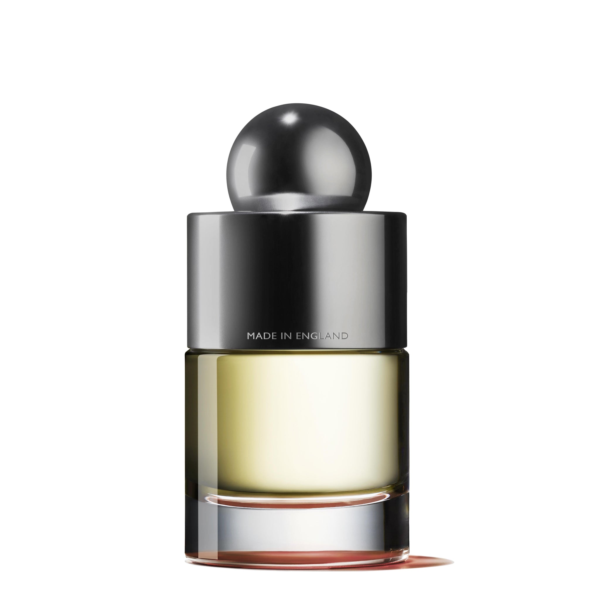 A sleek and modern perfume bottle featuring a cylindrical glass base filled with light yellow liquid, topped with a shiny metallic gray spherical cap. The bottle displays the text "Made in England" and contains the Re-charge Black Pepper Eau de Toilette 100ml fragrance by MoltonBrown Cyprus.