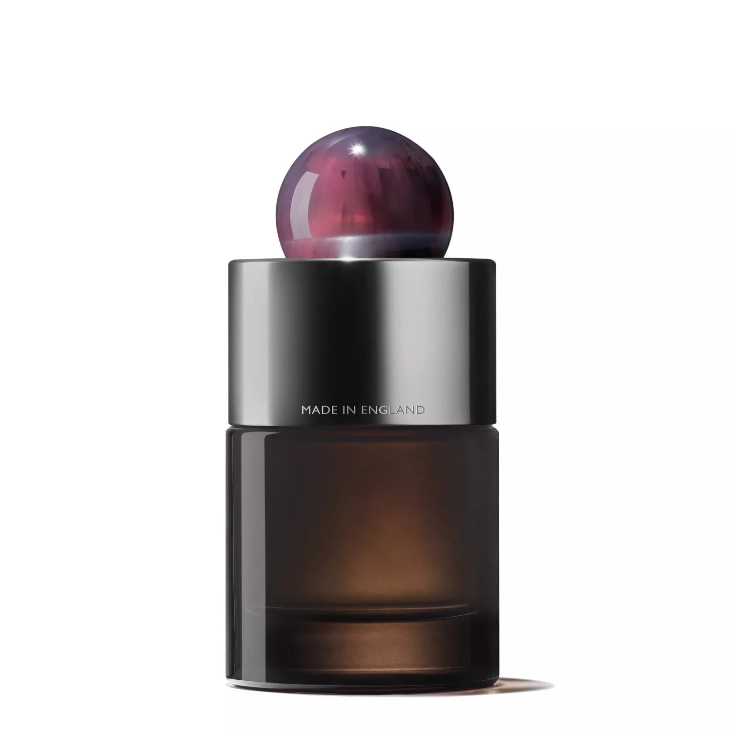 The Fiery Pink Pepper Eau de Parfum by MoltonBrown Cyprus features a sleek, cylindrical bottle with a dark base, metallic silver band engraved with Made in England, and a round marbled purple cap, highlighting its blend of patchouli and spicy pink pepper notes.