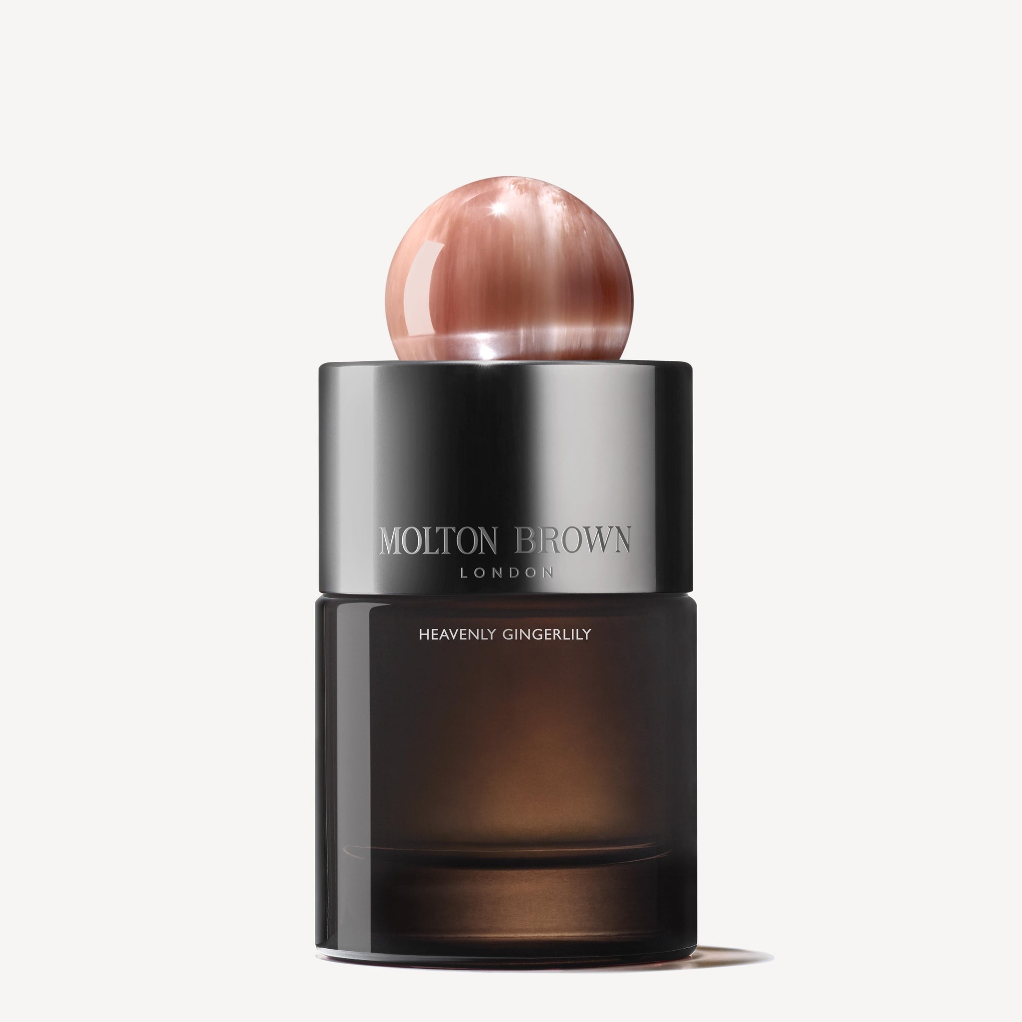 The Heavenly Gingerlily Eau de Parfum 100ml by MoltonBrown Cyprus offers an exotic escape. The design includes a dark glass base complemented by a shiny spherical cap, with MOLTON BROWN LONDON and HEAVENLY GINGERLILY elegantly printed on the front.