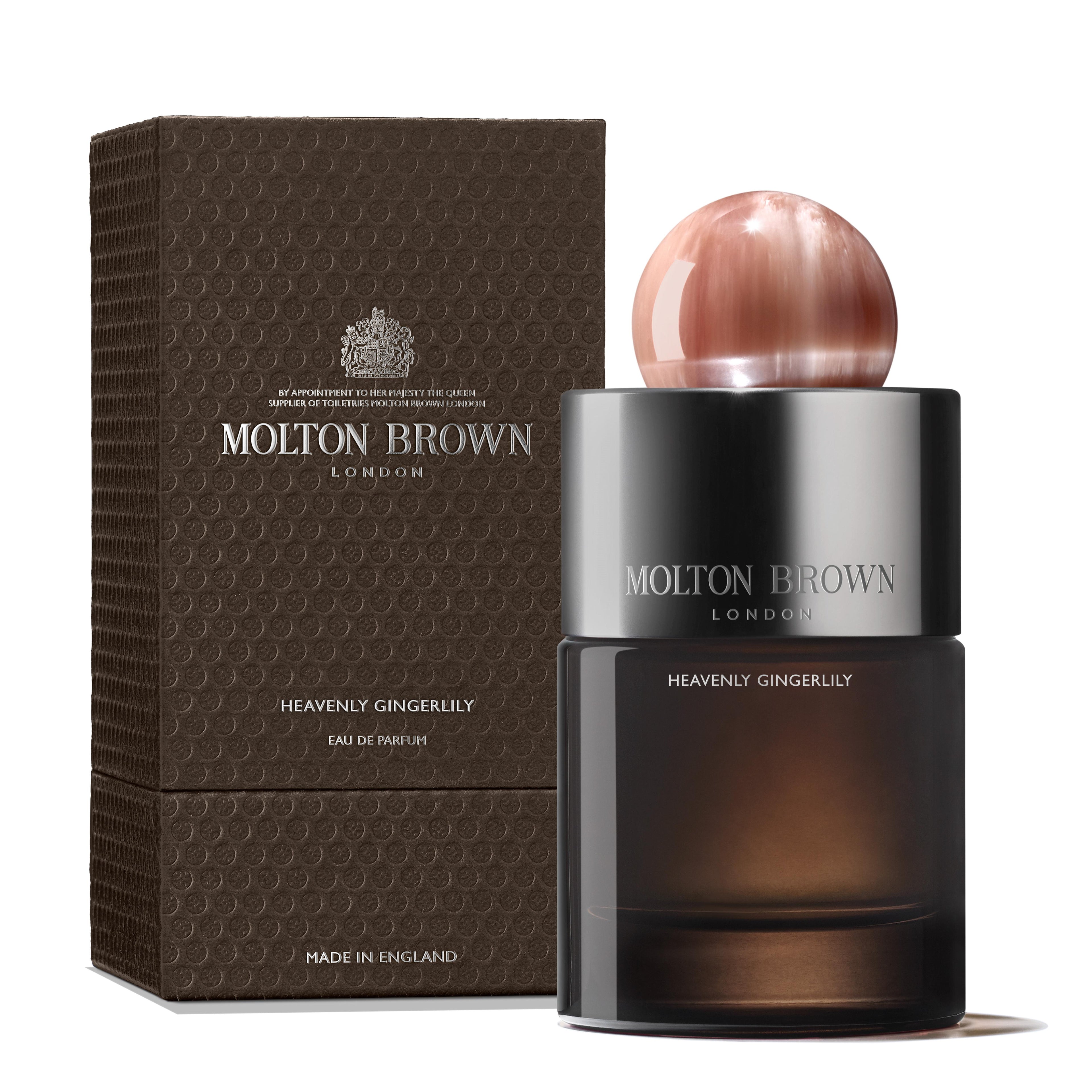 A 100ml bottle of MoltonBrown Cyprus Heavenly Gingerlily Eau de Parfum is displayed alongside its textured brown packaging. The bottle, featuring a spherical copper-colored cap, promises an exotic escape, with both the brand and product details prominently showcased.