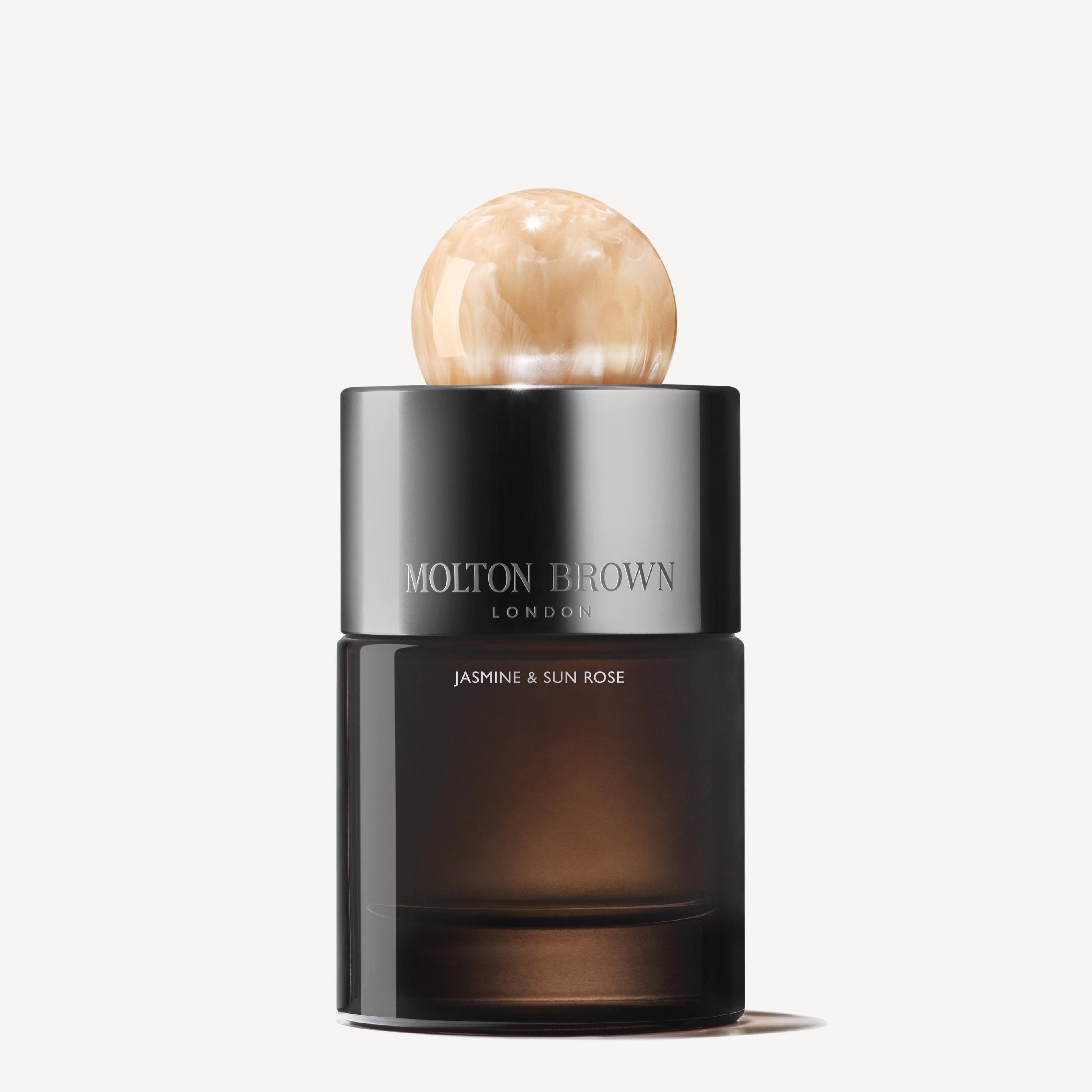 The Jasmine & Sun Rose Eau de Parfum 100ml from MoltonBrown Cyprus is housed in a stylish bottle that features a spherical marbled cap. Its sleek design, ideal for eveningwear, showcases a dark gradient with the brand name gracefully engraved on the upper part.