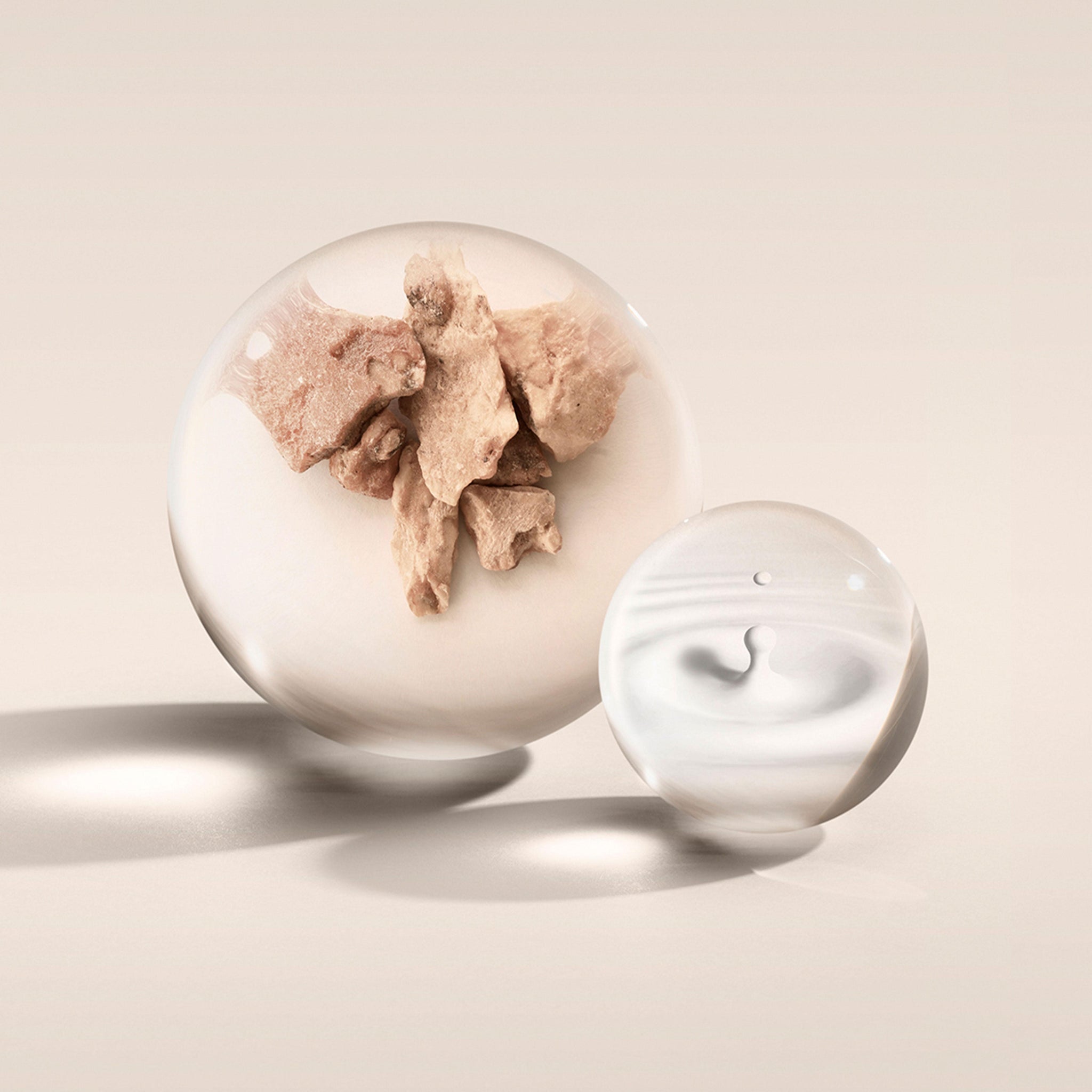 Two glass spheres rest on a tranquil beige surface. The larger sphere contains an array of irregular objects in a hue reminiscent of MoltonBrown Cyprus' Milk Musk Eau de Parfum. The smaller, translucent sphere showcases a subtle swirl pattern, echoing the gentle fragrance of this Eau de Parfum. Both cast soft shadows across the serene tableau.