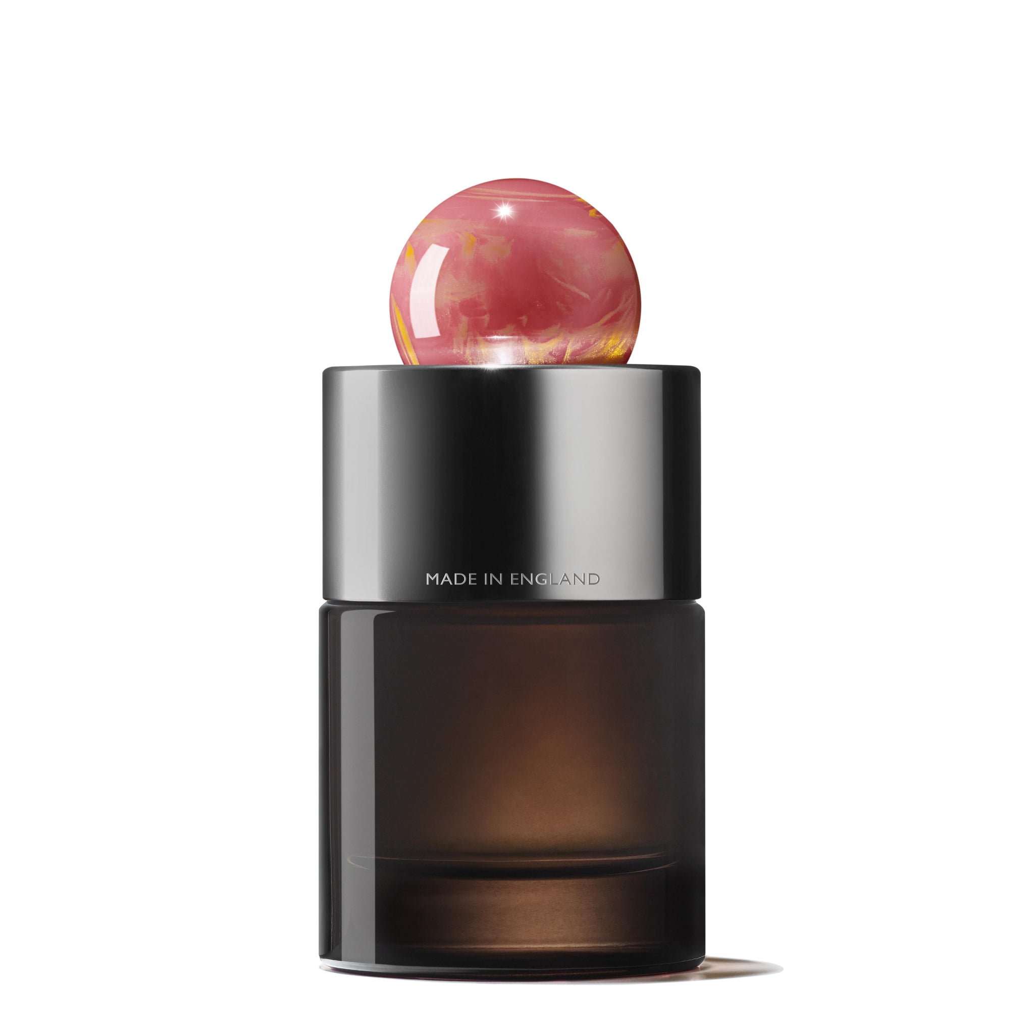 A stylish black bottle of Rose Dunes Eau de Parfum by MoltonBrown Cyprus features a reflective metallic cap and a marbled pink spherical topper. The text "MADE IN ENGLAND" is displayed on the bottle. Infused with a luxurious oudh accord, the perfume stands against a plain white background.