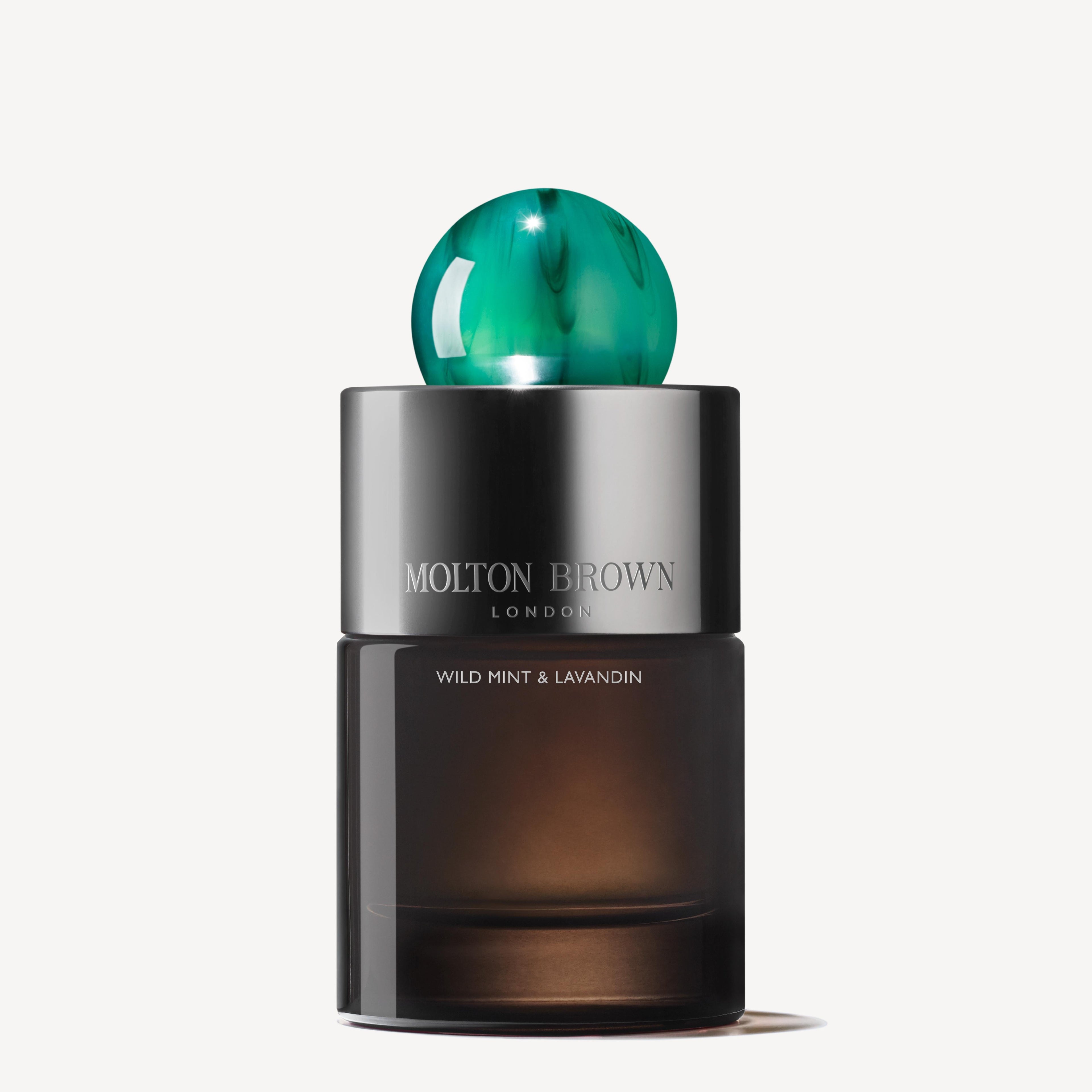 A bottle of Wild Mint & Lavandin Eau de Parfum 100ml from MoltonBrown Cyprus features a sleek, dark design with a unique round green cap, elegantly embodying the essence of wild mint and lavender notes.