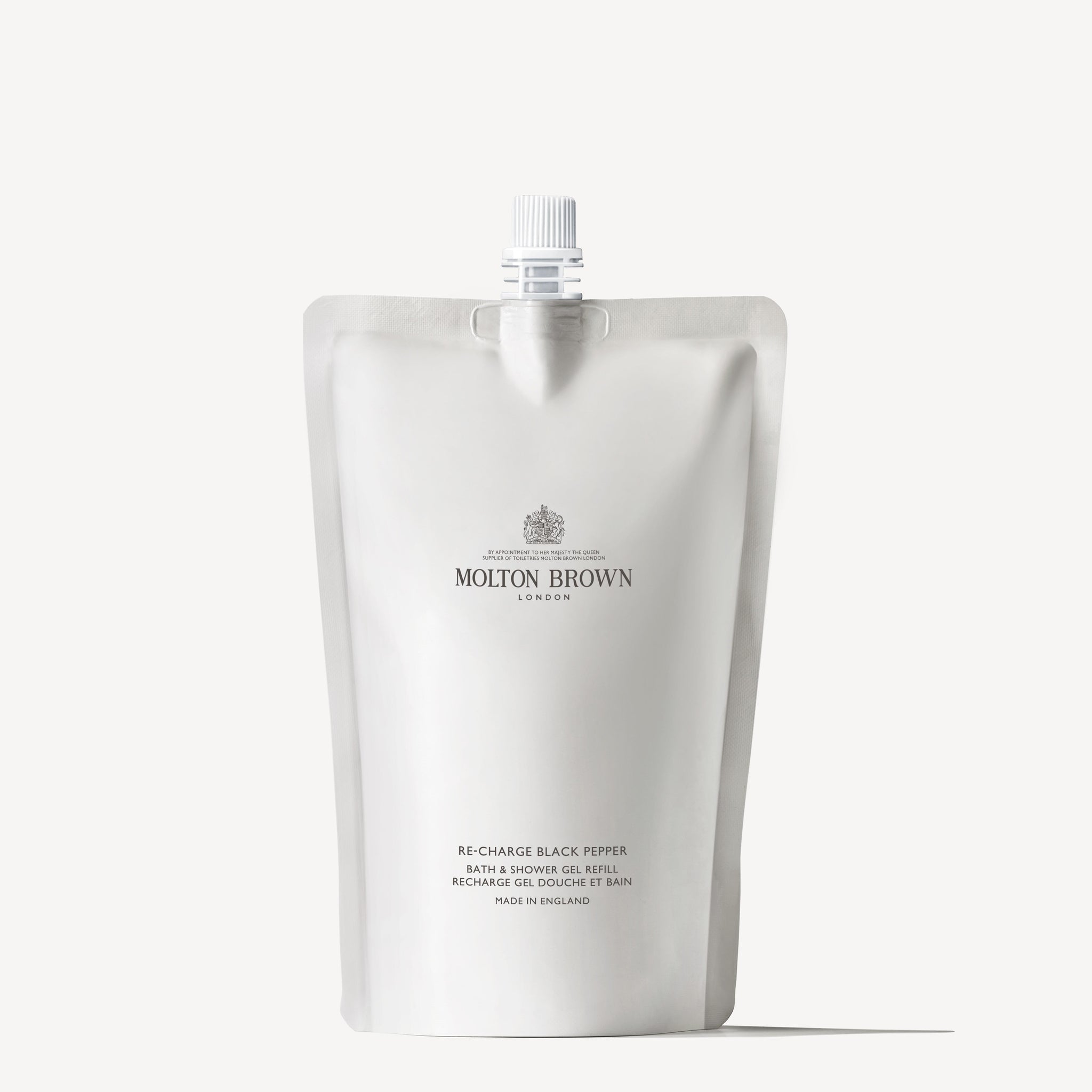 A MoltonBrown Cyprus sustainable refill pouch, labeled Re-charge Black Pepper Bath & Shower Gel Refill 400ml, rests against a plain background. The minimalist packaging features a spout at the top with text detailing the product name and brand.