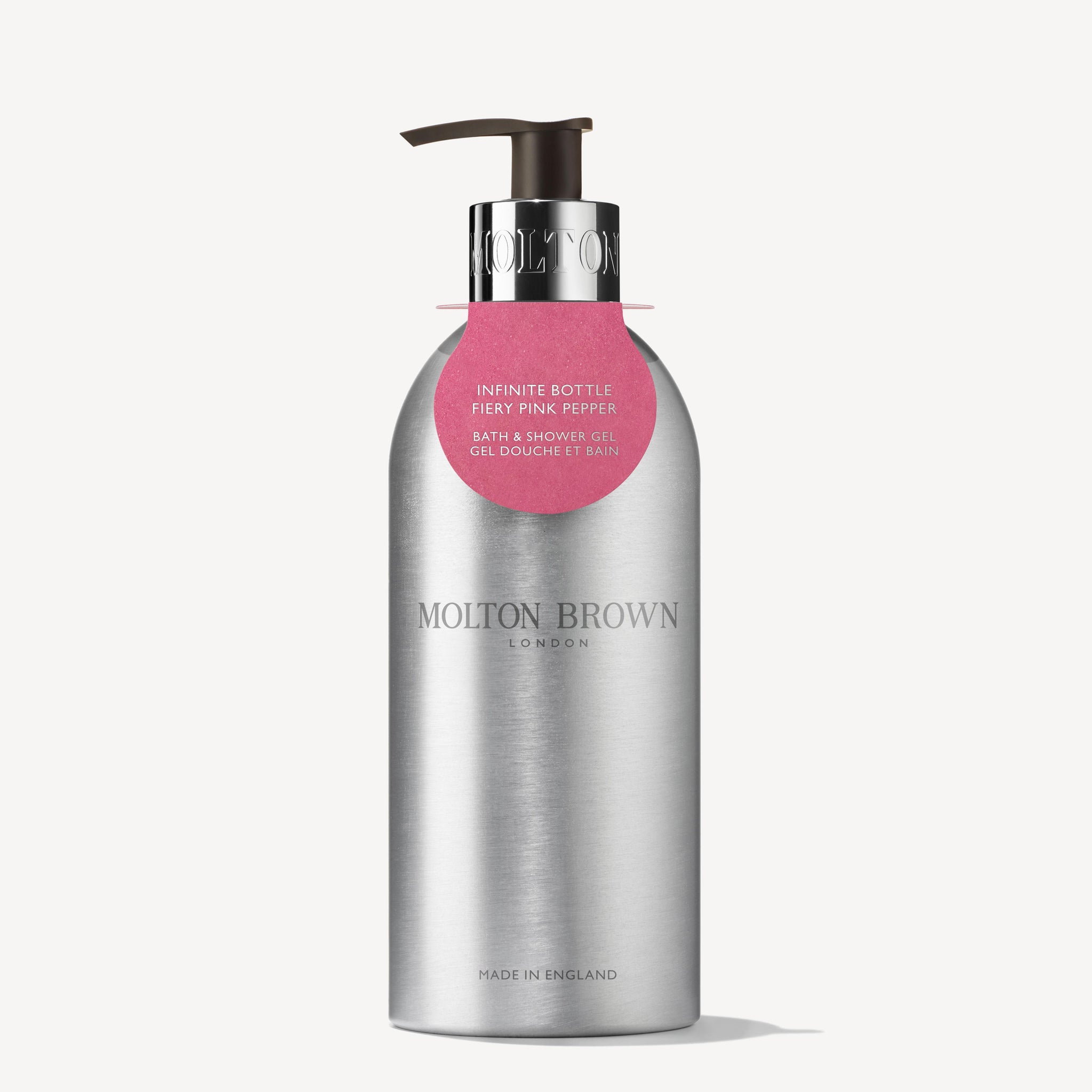 MoltonBrown Cyprus presents the Fiery Pink Pepper Infinite Bottle 400ml, a sleek silver pump bottle crafted from recycled aluminum. This woody-spicy body wash features a minimalist design with a small pink label and is a sustainable choice made in England.