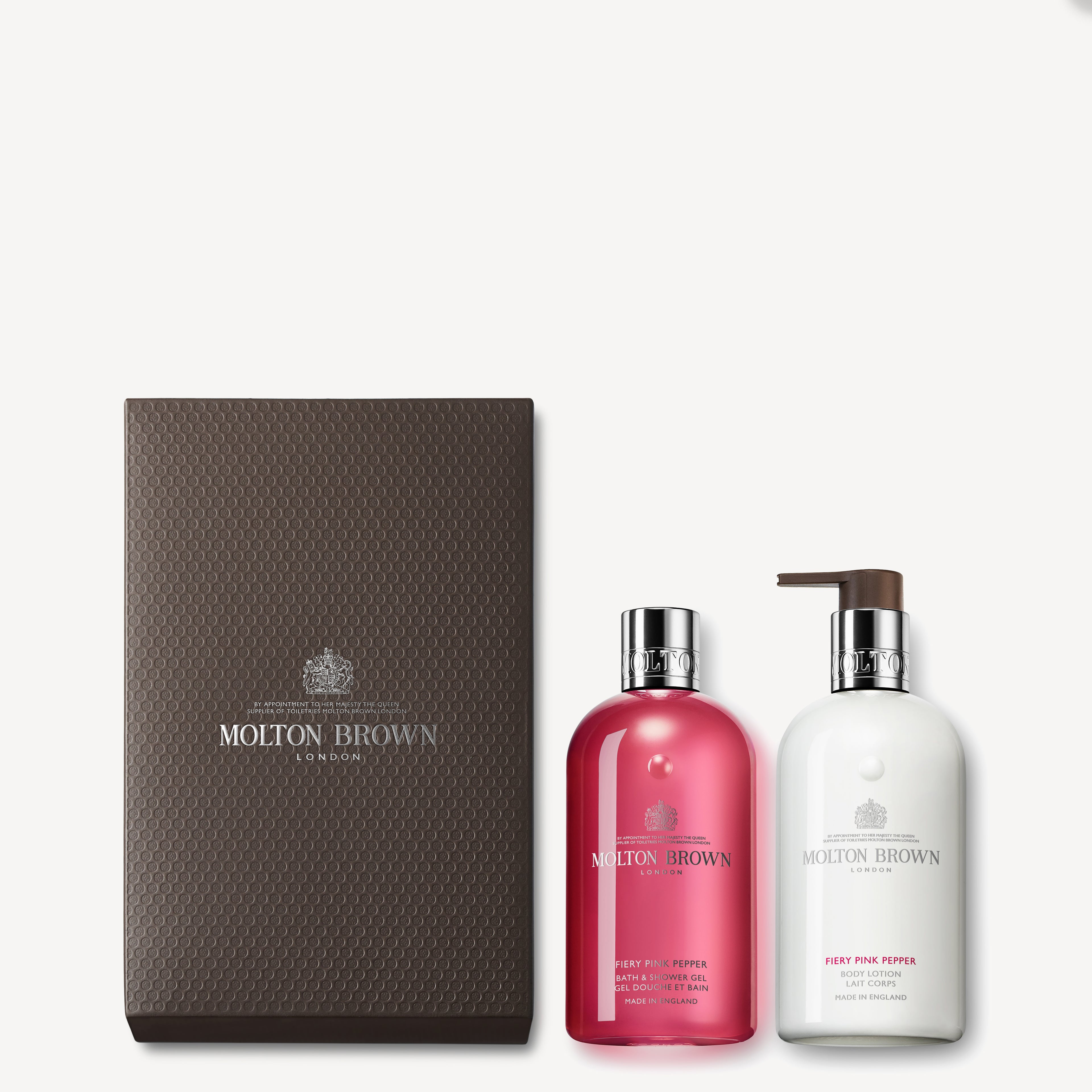 The Fiery Pink Pepper Shower Gel & Lotion Gift Set by MoltonBrown Cyprus includes two exquisite bottles: one containing the Fiery Pink Pepper shower gel and the other with luxurious white body lotion. Each bottle is topped with an elegant silver cap and beautifully packaged in a textured brown box featuring the distinguished Molton Brown logo.