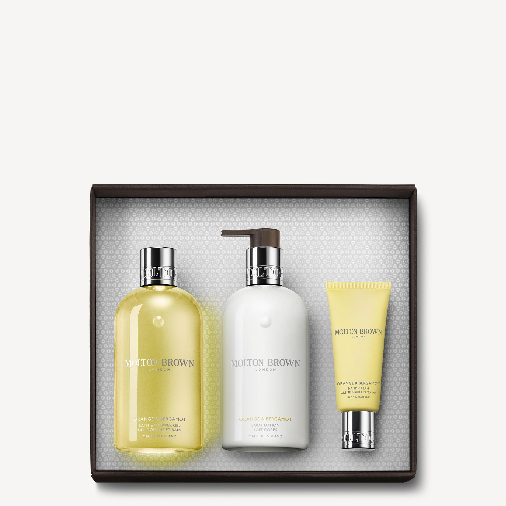 The Orange & Bergamot Pamper Gift Set by MoltonBrown Cyprus offers a luxurious collection featuring bath and shower gel, body lotion, and hand cream infused with Neroli Flower. The set is beautifully packaged in a white box with an elegantly textured interior.