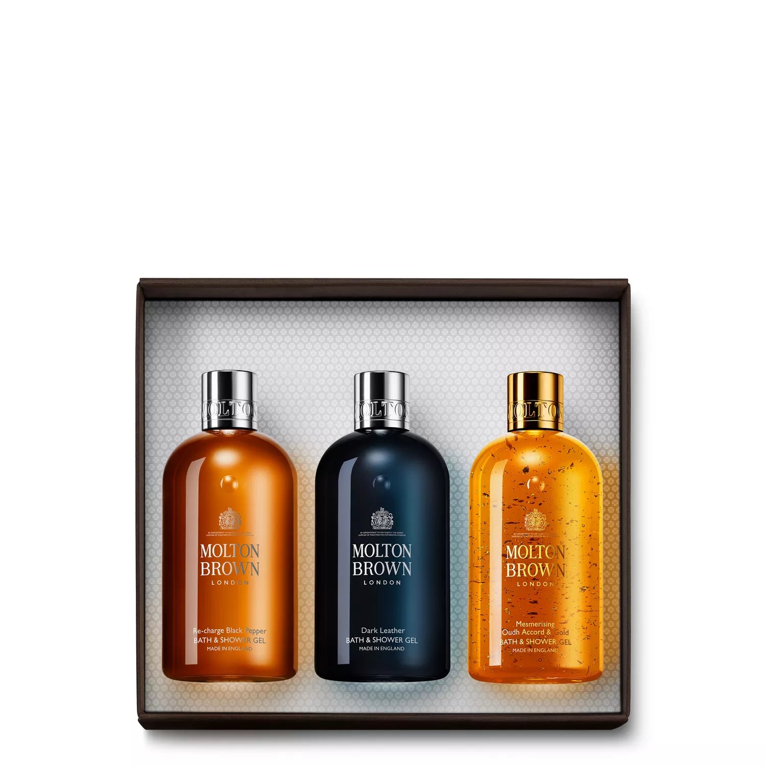 Explore the MoltonBrown Cyprus Woody Gift Set featuring three bath and shower gels: Mesmerising Oudh Accord & Gold, Orange & Bergamot, and Dark Leather. Each bottle has a luxurious silver or gold cap, elegantly presented on a textured white background.