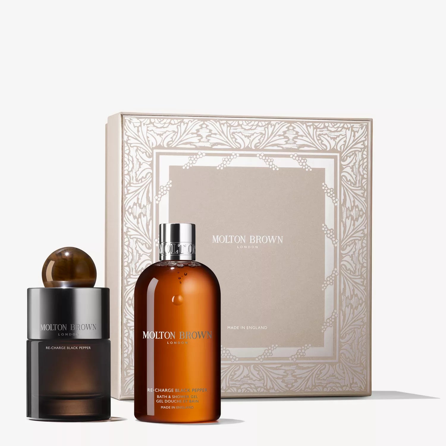 The MoltonBrown Cyprus Re-charge Black Pepper Fragrance Gift Set includes an Eau de Parfum with a dark cap, an amber bath and shower gel, and a beige box with silver details and the Molton Brown logo.