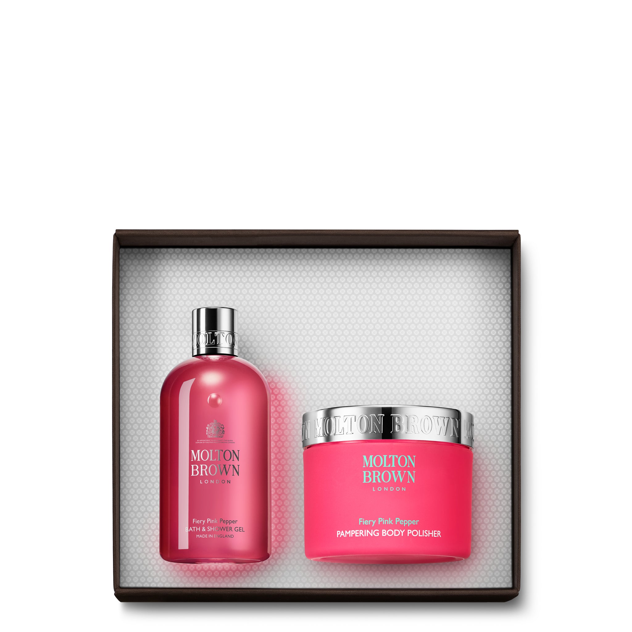 The Fiery Pink Pepper Enriching Body Gift Set from MoltonBrown Cyprus contains a tall, pink shower gel bottle featuring a silver cap and a round body scrub jar with a silver lid. Both items are infused with the vibrant scent of Fiery Pink Pepper.