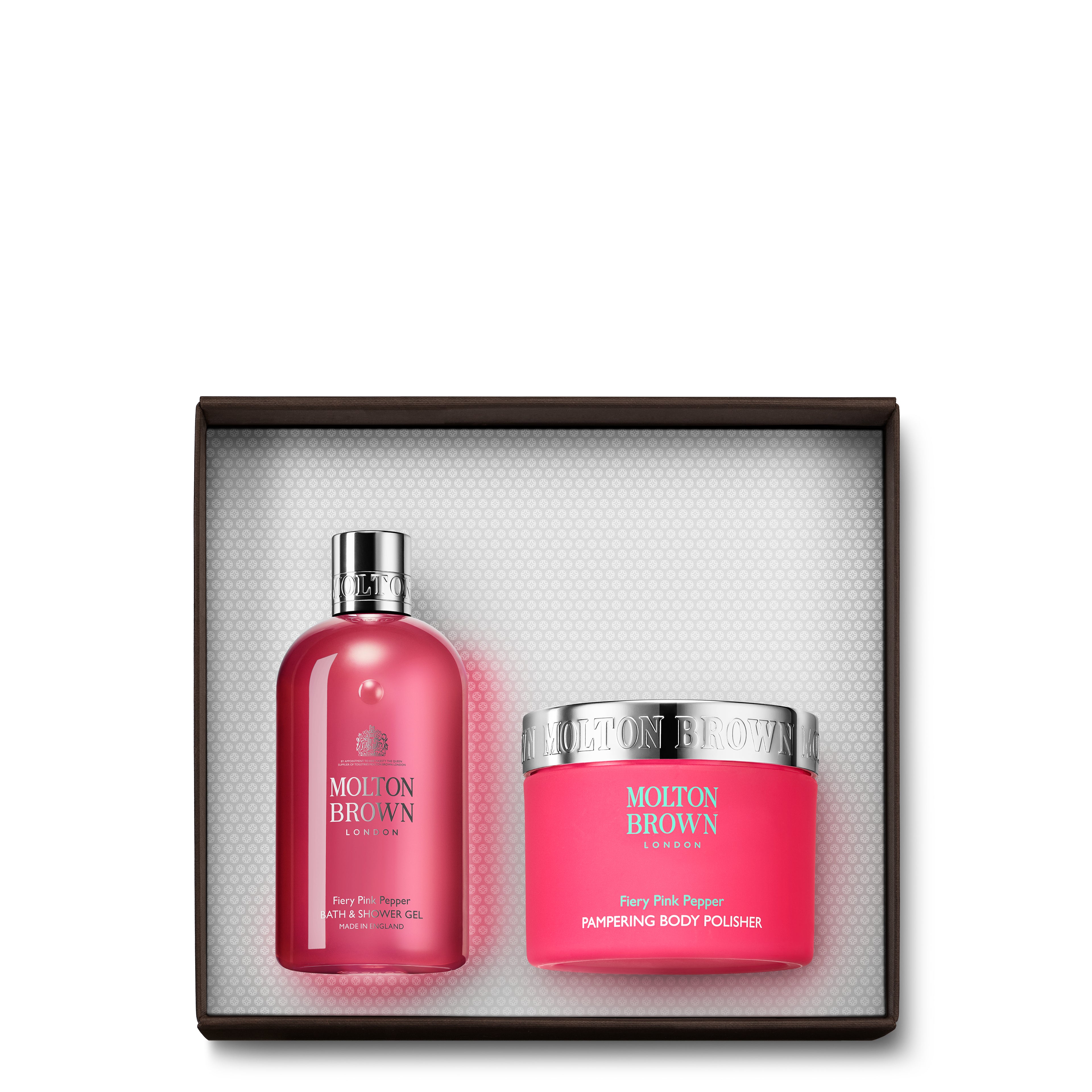 The Fiery Pink Pepper Enriching Body Gift Set from MoltonBrown Cyprus contains a tall, pink shower gel bottle featuring a silver cap and a round body scrub jar with a silver lid. Both items are infused with the vibrant scent of Fiery Pink Pepper.