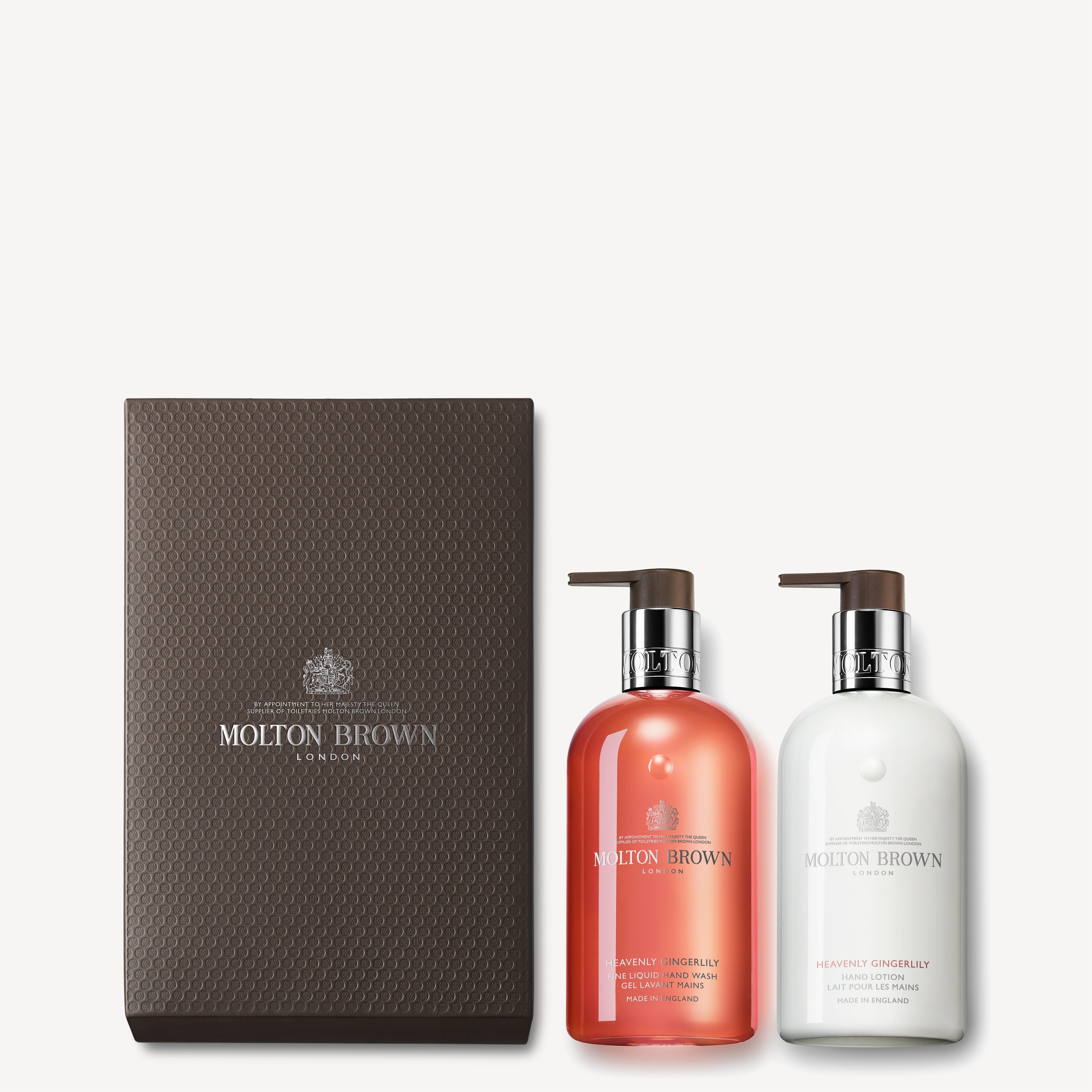 A sophisticated display showcases the MoltonBrown Cyprus Heavenly Gingerlily Hand Wash & Lotion Set, featuring a brown textured box and two pump bottles—one pink and one white. The set includes both a luxurious Hand Lotion and Liquid Hand Wash, while the serene background maintains a light, calming color.